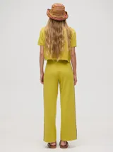 Pantalón de punto color verde oliva, confeccionado en algodón, con corte holgado, pierna ancha y tiro alto. Cuenta con pretina elástica con cordón de ajuste y una línea lateral a contratono en color naranja.