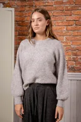 Sweater de tejido de punto con textura tipo mohair, color gris jaspeado con sutiles tonos pasteles, de corte holgado, cuello redondo y mangas largas con puños ajustados.