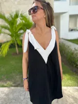 Vestido corto color beige, con escote en V con borde blanco, breteles anchos con lazos y corte holgado.