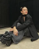 Borcego negro de cuero con plataforma track y detalles metálicos. Ajuste con cordones y hebillas.
