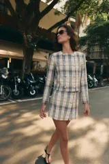 Falda pantalón de tiro alto confeccionada en tejido de tweed con estampado a cuadros en tonos beige, azul y negro. Presenta detalles de falsos botones y cierre lateral con cremallera oculta.