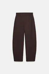 Pantalón de tiro medio color marrón oscuro con textura acanalada o plisada verticalmente. Presenta pierna ancha y cintura con trabillas.