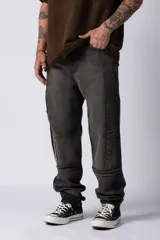 Pantalón de jean con lavado oxidado, de corte mom y tiro medio. Presenta costuras verticales visibles y detalles de terminaciones deshilachadas en las piernas.