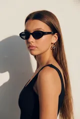 Lentes de sol con armazón ovalado de acetato negro y micas oscuras.