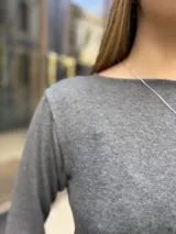 Remera gris de manga larga con escote redondo, confeccionada en tejido elastizado de ajuste al cuerpo.