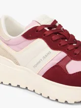 Zapatillas Tommy Jeans modelo Cleated Runner Suede Mix, de diseño urbano y deportivo con combinación de colores rosa, bordó, beige y blanco. Presentan suela dentada y detalles de la marca en el lateral.
