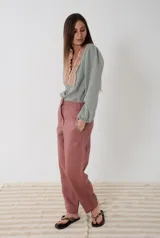 Camisa de voile de algodón color verde gastado con escote en V y aplique de guarda bordada en punto smock tostado. Presenta mangas largas abullonadas con puños elásticos y cierre frontal con pequeños botones de nácar.