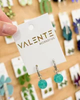 Aros tipo argolla de acero con dije colgante de esfera de piedra color turquesa.