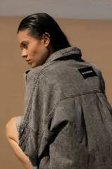 Vestido camisero corto de denim azul, con cuello camisero, cierre frontal con botones y mangas largas con puños abotonados.