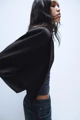 Blazer corto de corte recto con cuello de solapa, manga larga y hombreras. Presenta un diseño minimalista sin botones y forro interior a tono.