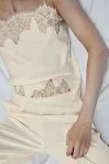 Pantalón de tiro alto confeccionado en tejido satinado, con cintura elástica y bolsillos laterales. Presenta un diseño de corte recto con bajo acabado en aplicación de encaje a tono.