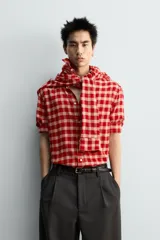 Camisa de corte relajado confeccionada en tejido de mezcla de viscosa y lana con acabado de franela. Presenta un diseño de cuadros en tonos rojo y beige, cuello con botones, cierre frontal de botones y mangas largas con puños abotonados.