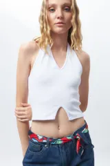 Crop top blanco de algodón, sin mangas, con cuello halter y abertura en el frente.
