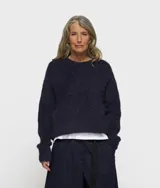 Sweater corto de punto color azul marino, de corte holgado y cuello redondo. Confeccionado en una mezcla de alpaca y lana cepillada con acabado suave y ribetes elásticos.