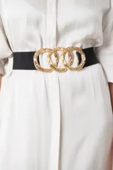 Cinto elástico negro con hebilla dorada formada por tres aros entrelazados.
