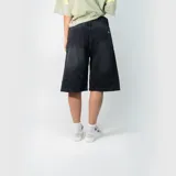 Bermuda de jean estilo baggy en color negro lavado, con corte holgado, tiro medio y cierre frontal con botón y cremallera.