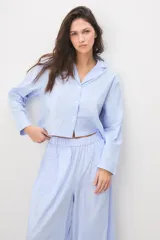 Pijama de algodón a rayas celestes y blancas, compuesto por una camisa de manga larga con botones y un pantalón largo de corte ancho.