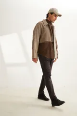 Camisa estilo leñadora con diseño patchwork en tonos marrones y beige. Presenta coderas, cartera americana y bolsillo ojal en el delantero. Confeccionada en Uruguay con tela 100% lana fina sin teñir.