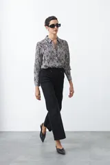 Pantalón negro de tiro alto, corte recto y silueta clásica. Presenta costuras verticales marcadas en la parte delantera de las piernas.