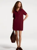 Vestido corto de estilo polo confeccionado en tejido de punto piqué, color bordó. Presenta cuello clásico, escote con abertura y mangas cortas.