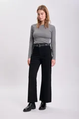 Pantalon de jean negro de corte ancho y tiro alto, con cierre frontal y bolsillos. Presenta un acabado deshilachado en el ruedo.