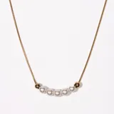 Collar dorado con cadena fina y dije con perlas blancas y bolitas doradas.