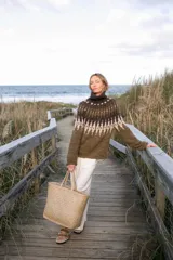 Sweater de lana merino con cuello alto, diseño de tejido artesanal con patrón geométrico en tonos verde oliva, marrón oscuro y beige.