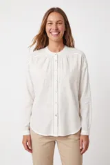Camisa blanca de manga larga con cuello mao, cierre frontal con botones y delicados bordados florales en el frente.
