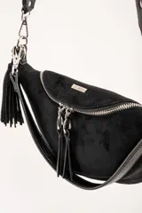 Cartera tipo bandolera de tamaño pequeño, confeccionada en material sintético con textura de gamuza en color marrón topo. Presenta un diseño semicircular con cierre superior, herrajes metálicos plateados y una correa larga ajustable de cinta técnica.