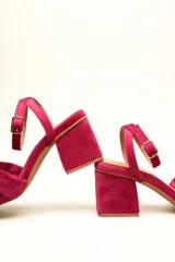 Sandalia de tacón cuadrado medio, confeccionada en terciopelo negro. Presenta un diseño de tiras cruzadas con nudo en la parte delantera y una tira ajustable con hebilla en el tobillo.