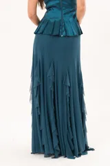 Pollera larga confeccionada en microtul color verde petroleo, totalmente forrada, de diseño fluido con volados que aportan movimiento y caída liviana.
