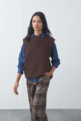 Chaleco de punto con textura afelpada, cuello redondo y hombros marcados. Presenta una silueta relajada y un diseño sin mangas.
