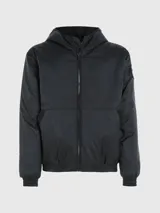 Campera cortavientos negra con capucha, confeccionada en poliéster reciclado. Cuenta con cierre de cremallera, puños y bajo elásticos, bolsillos laterales y logo de Calvin Klein en la manga.