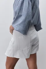 Short pollera de tiro alto confeccionado en algodón, con diseño cruzado en el delantero que simula una falda, cierre lateral invisible y bolsillos traseros.
