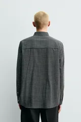 Camisa de corte regular fit confeccionada en una mezcla de lana y algodón. Presenta un diseño de cuadros pequeños, cuello solapa, manga larga con puños abotonados y cierre frontal con botones. Incluye un bolsillo en el pecho.
