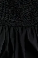 Vestido largo color negro con cuerpo de crochet en la parte superior, escote halter con tirantes finos y falda fluida con leve vuelo confeccionada en mezcla de lyocell. Presenta diseño de espalda descubierta.