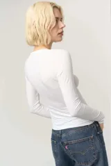Remera de manga larga blanca, confeccionada en jersey liviano de tacto suave, con escote en V limpio y calce que acompaña el cuerpo.