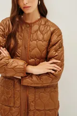 Campera acolchada color marrón con diseño de costuras en forma de corazones, cuello redondo, cierre frontal con botones a presión y ribetes en contraste.