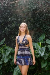 Vestido corto negro con estampado de plumas doradas, escote en V, breteles finos cruzados en la espalda, cut-outs laterales y volado en el ruedo.