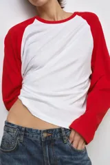 Remera oversize de manga larga estilo raglán, con cuerpo blanco y mangas y cuello en color rojo.