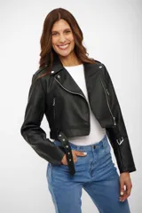 Campera estilo biker corta, color negro, confeccionada en cuerina (poliuretano) con forro de poliéster. Presenta solapas con broches, cierre asimétrico plateado, bolsillos con cierres y un cinturón con hebilla en el ruedo inferior.