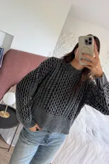 Sweater de tejido de punto con diseño de ochos en relieve, color gris oscuro con detalles en negro. Presenta cuello redondo alto y puños y ruedo acanalados.