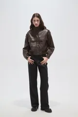 Campera de eco-cuero negro con cuello alto, cierre frontal, bolsillos con solapa en el pecho y puños y ruedo elásticos.