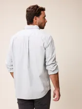 Camisa de manga larga en color blanco, confeccionada en algodón. Presenta cuello abotonado, cierre frontal con botones y un bolsillo en el pecho.