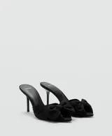 Sandalias de tacón alto estilo destalonado, color negro, con puntera abierta y detalle de lazo en la parte frontal.