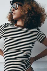 Camiseta de manga corta con estampado de rayas horizontales blancas y negras, cuello redondo y ribetes en color marrón.