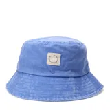 Gorro tipo bucket color celeste con efecto lavado, presenta un parche cuadrado de tela en el frente con inscripción circular.