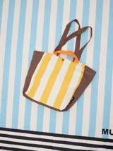 Bolso tipo tote con diseño de rayas verticales en amarillo y blanco, con laterales, base y correas en color marrón. Incluye asas cortas en color naranja y cierre con botón a presión.