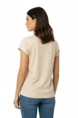Remera de algodón color beige con cuello redondo y mangas cortas con dobladillo. Presenta un estampado frontal con diseño botánico y texto en tonos marrones.