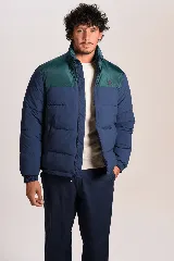 Campera puffer bicolor para hombre, con diseño acolchado, cuello alto, cierre frontal y combinación en azul y verde oscuro.